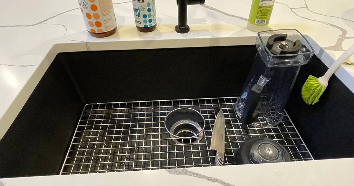 Black farmhouse kitchen sink with quartz countertop and matte black faucet in modern kitchen remodel