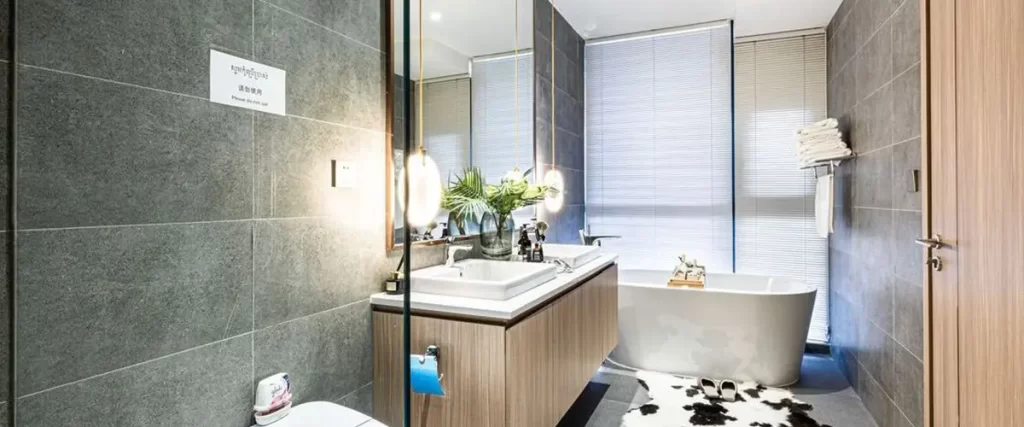 Contemporary bathroom renovation with freestanding tub, wood vanity, and gray tile walls