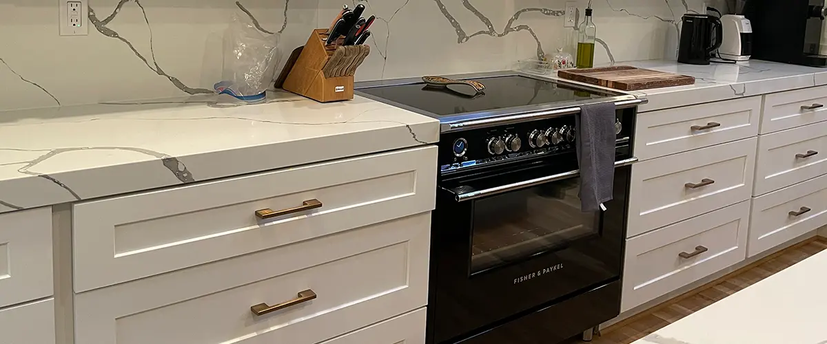 Custom kitchen renovation with quartz backsplash, white cabinetry, and luxury appliances