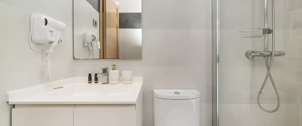 Small modern bathroom remodel with white vanity, walk-in shower, and minimalist design