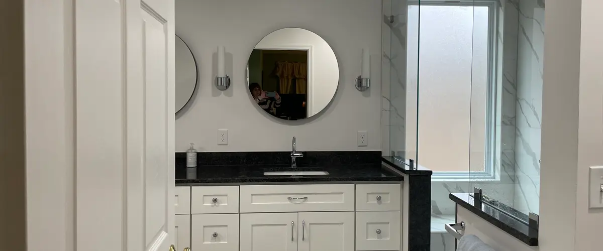 Bathroom remodeling featuring white shaker vanity, black granite countertop, and glass walk-in shower