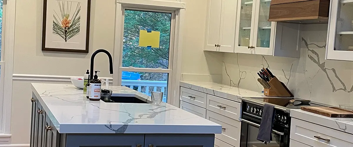 Kitchen remodeling with quartz waterfall island, white shaker cabinets, and custom wood range hood